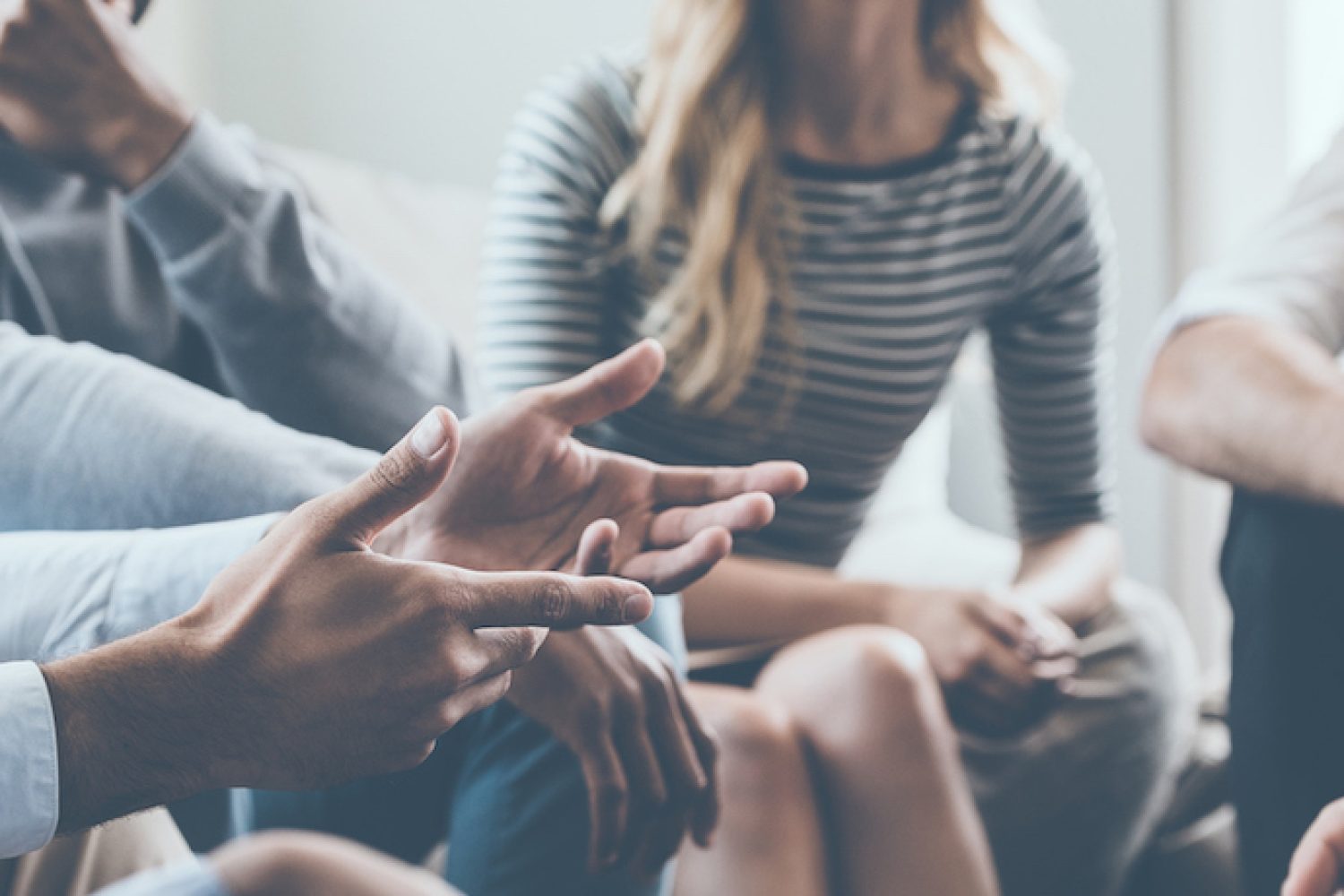Close-up of people communicating while sitting in circle and gesturing